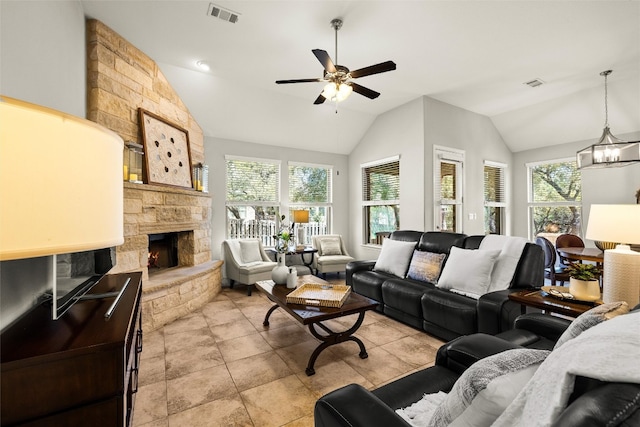 living room with visible vents, a stone fireplace, vaulted ceiling, and ceiling fan with notable chandelier