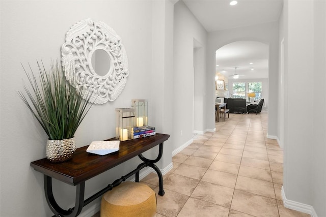 hall featuring arched walkways, recessed lighting, baseboards, and light tile patterned flooring