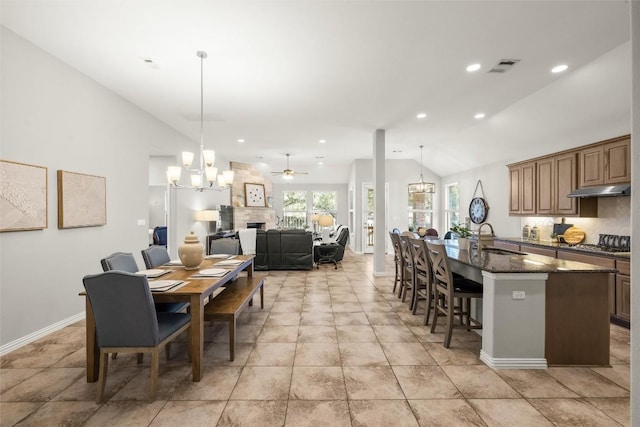 dining area featuring visible vents, recessed lighting, a fireplace, vaulted ceiling, and ceiling fan with notable chandelier