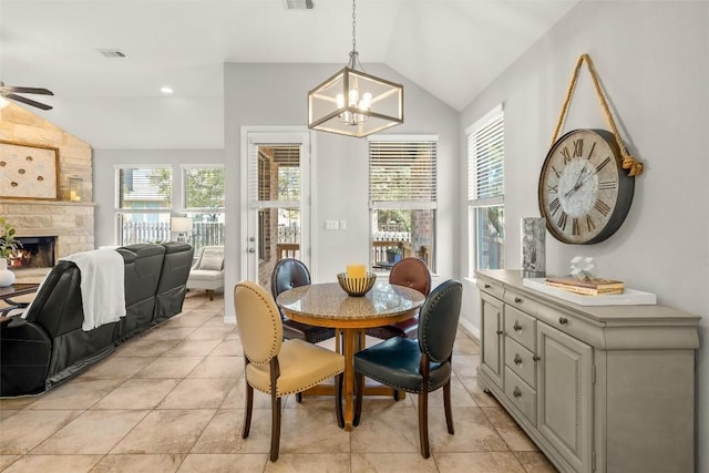 dining area featuring visible vents, ceiling fan with notable chandelier, a fireplace, light tile patterned floors, and vaulted ceiling