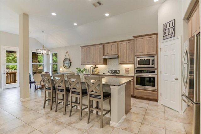 kitchen with lofted ceiling, tasteful backsplash, a kitchen island with sink, visible vents, and appliances with stainless steel finishes