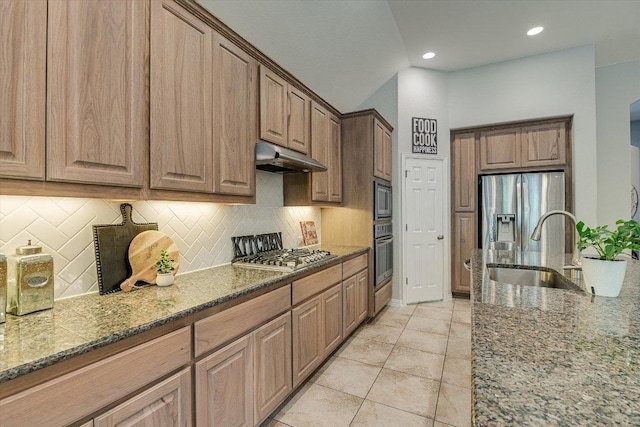 kitchen with under cabinet range hood, appliances with stainless steel finishes, a sink, and decorative backsplash