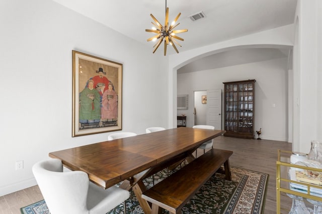 dining room featuring wood finished floors, visible vents, arched walkways, and a chandelier