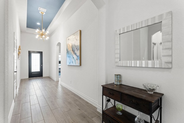 entrance foyer featuring baseboards, arched walkways, and wood finish floors