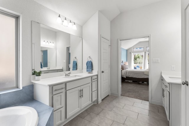 bathroom featuring tile patterned floors, two vanities, a sink, ensuite bath, and vaulted ceiling