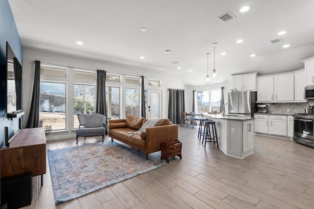 living area featuring recessed lighting, visible vents, and light wood finished floors