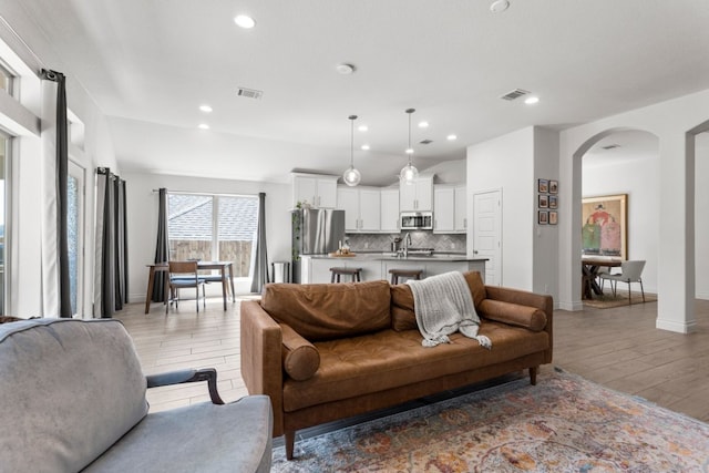 living room with recessed lighting, visible vents, arched walkways, and light wood-style floors