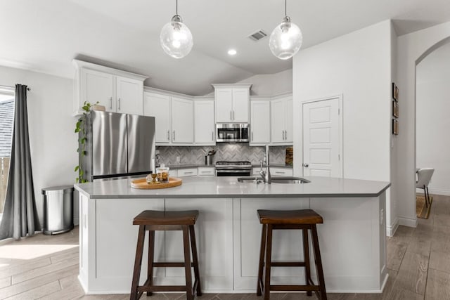 kitchen featuring visible vents, decorative backsplash, appliances with stainless steel finishes, light wood-style floors, and a sink