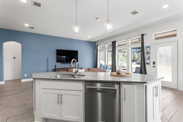 kitchen with visible vents, open floor plan, stainless steel dishwasher, white cabinetry, and a sink