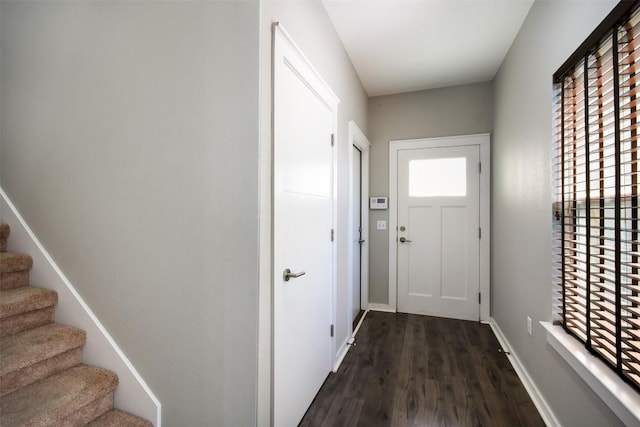 doorway with baseboards, dark wood-type flooring, and stairs