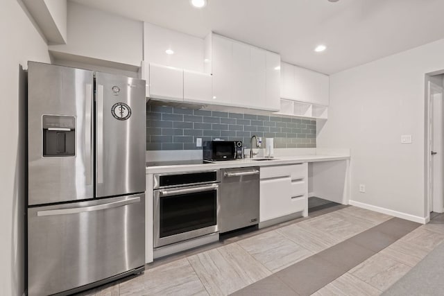 kitchen featuring black appliances, light countertops, decorative backsplash, white cabinetry, and a sink