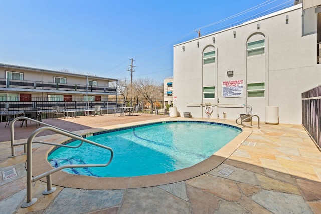 community pool with a patio and fence