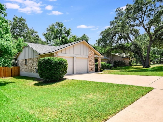 view of front of property featuring a front yard, fence, concrete driveway, a garage, and board and batten siding