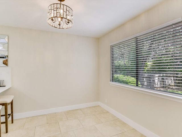 unfurnished room featuring a chandelier, light tile patterned floors, and baseboards