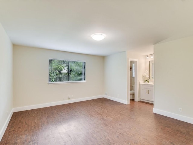 spare room featuring baseboards and wood finished floors