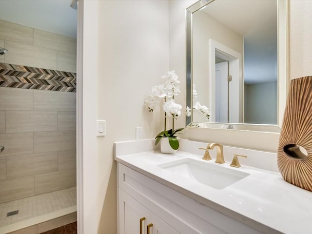 bathroom with a tile shower and vanity