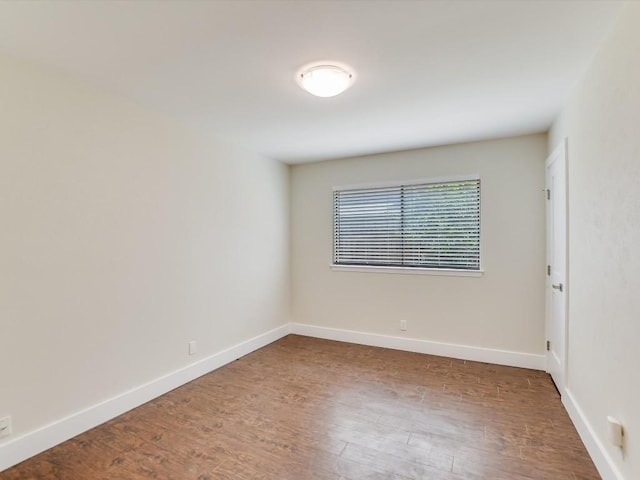 spare room with baseboards and wood finished floors