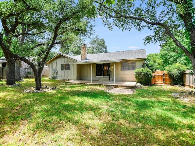 rear view of property featuring a patio, a fenced backyard, a yard, board and batten siding, and a chimney