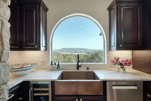 kitchen with dark brown cabinets, backsplash, wine cooler, stainless steel dishwasher, and a sink