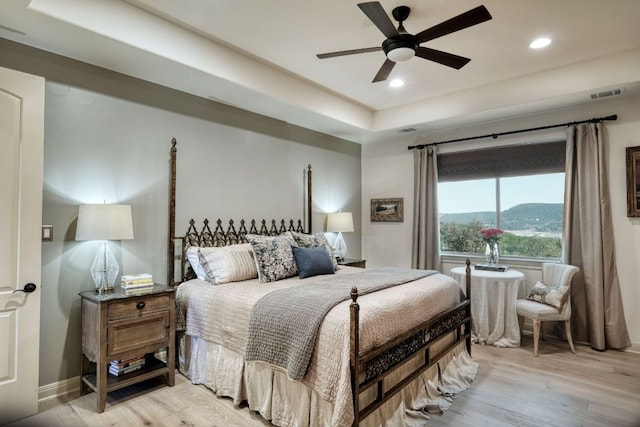 bedroom with visible vents, a tray ceiling, recessed lighting, light wood finished floors, and baseboards