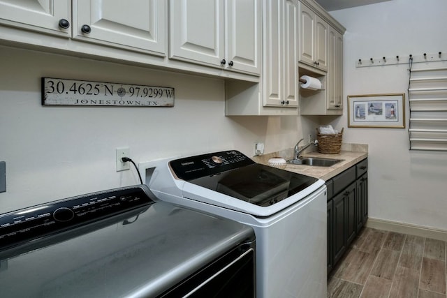 laundry room with washing machine and clothes dryer, baseboards, wood finish floors, cabinet space, and a sink