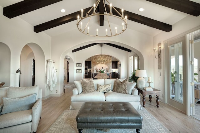 living room with arched walkways, plenty of natural light, an inviting chandelier, and light wood finished floors