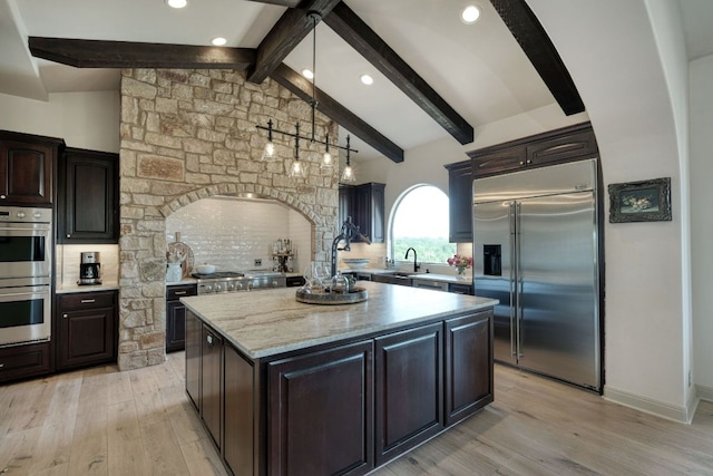 kitchen featuring a center island, beam ceiling, stainless steel appliances, and light wood-type flooring