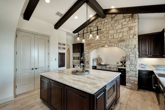 kitchen featuring light wood finished floors, visible vents, lofted ceiling with beams, arched walkways, and stainless steel appliances