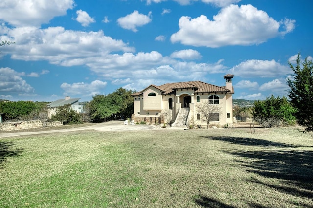 view of front of property with a front lawn, a tiled roof, stucco siding, and a chimney