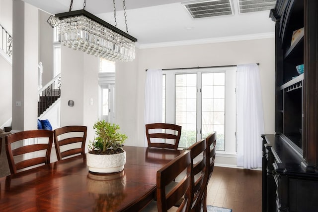 dining space with visible vents, crown molding, dark wood-type flooring, a chandelier, and stairs