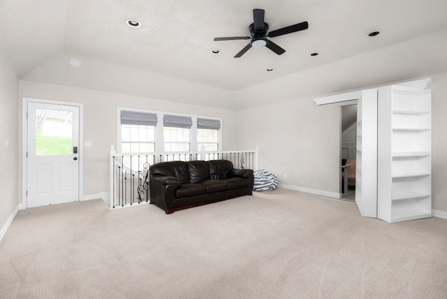 living area featuring baseboards, light colored carpet, ceiling fan, and vaulted ceiling