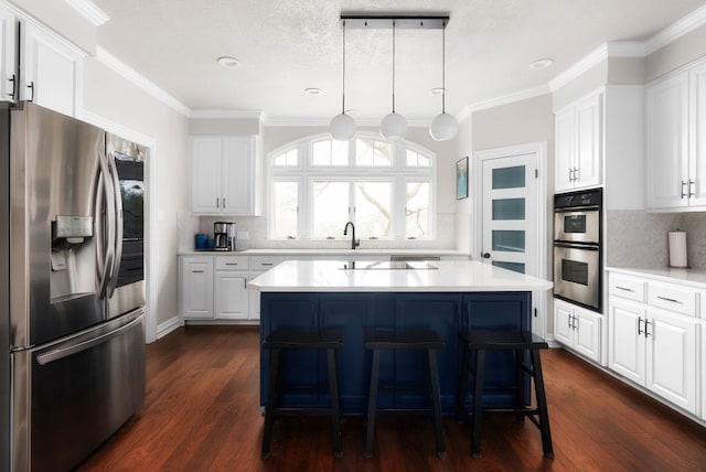 kitchen featuring a kitchen island, light countertops, appliances with stainless steel finishes, a kitchen breakfast bar, and dark wood-style floors