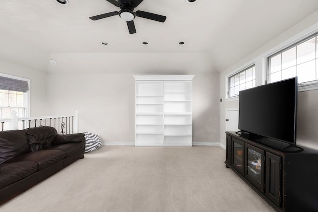 living area with lofted ceiling, light colored carpet, baseboards, and ceiling fan