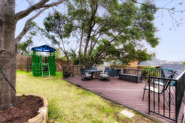 wooden deck with a playground, a fenced backyard, and a lawn