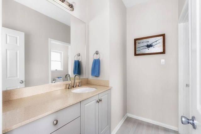 bathroom with baseboards, toilet, wood finished floors, and vanity