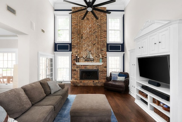 living room featuring ceiling fan, visible vents, ornamental molding, and dark wood finished floors