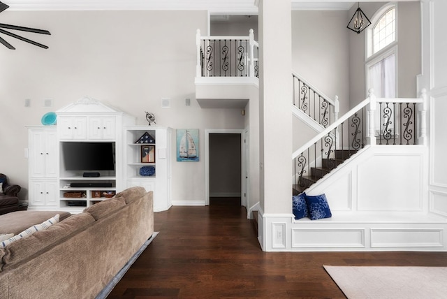 living area with dark wood finished floors, a high ceiling, stairs, and ceiling fan with notable chandelier