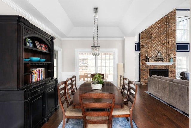 dining space featuring a wainscoted wall, a fireplace, a decorative wall, dark wood-style flooring, and vaulted ceiling