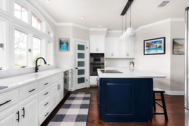 kitchen with dark wood-style flooring, visible vents, appliances with stainless steel finishes, and a sink