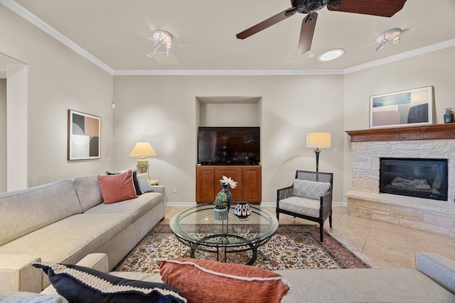 living room featuring tile patterned floors, a fireplace, crown molding, baseboards, and ceiling fan