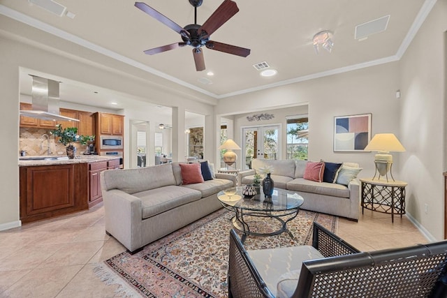 living area featuring light tile patterned floors, baseboards, visible vents, ceiling fan, and crown molding