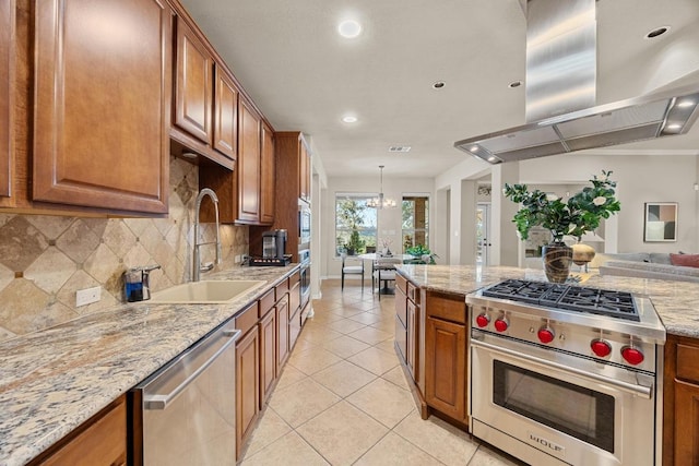 kitchen featuring brown cabinetry, island exhaust hood, a sink, appliances with stainless steel finishes, and tasteful backsplash