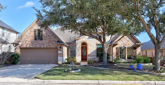 view of front of house with brick siding, an attached garage, a front lawn, stone siding, and driveway