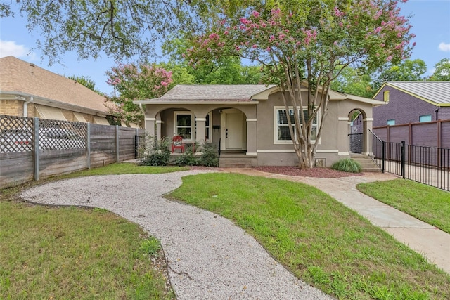 view of front facade with covered porch, stucco siding, a front yard, and fence