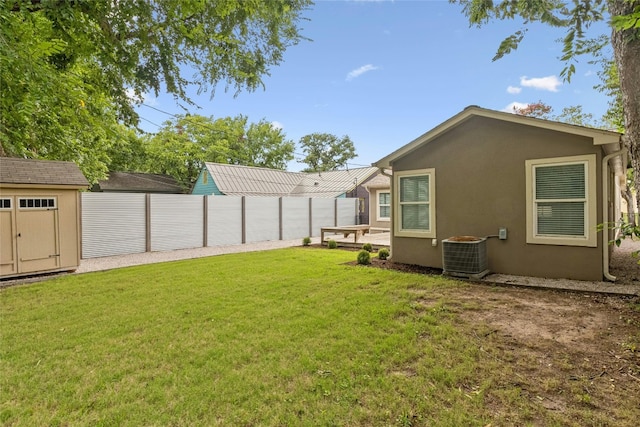 view of yard with an outbuilding, central AC unit, a storage shed, and fence