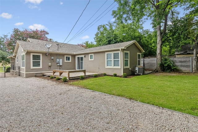 back of property with gravel driveway, a yard, fence, and stucco siding