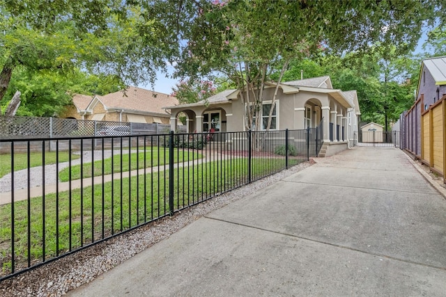 view of front of house featuring a front yard, a gate, driveway, stucco siding, and a fenced front yard