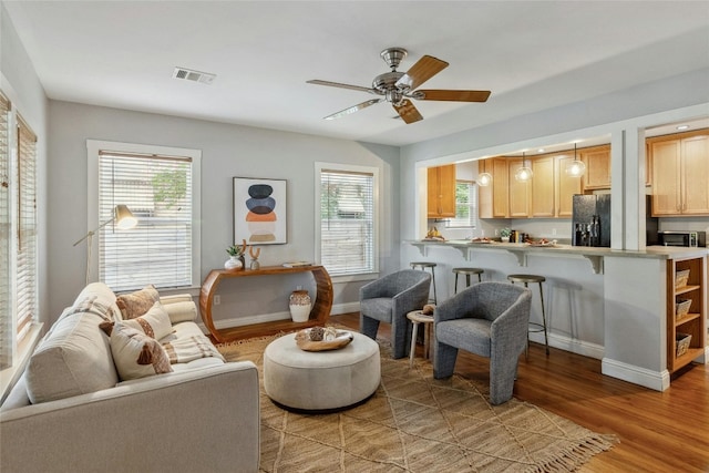 living room featuring visible vents, plenty of natural light, light wood-style floors, and ceiling fan