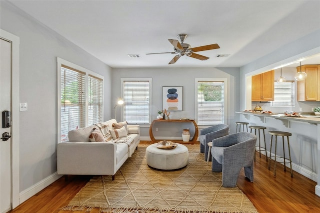 living area with light wood-type flooring, baseboards, and a ceiling fan