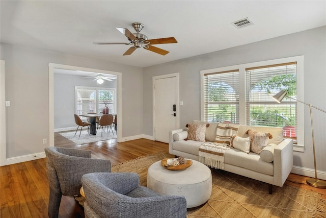 living room with visible vents, baseboards, and wood finished floors